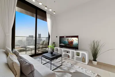 a living room with a couch and a tv on a wall at Stylish 1BR w Skyline Views & Balcony in Dubai