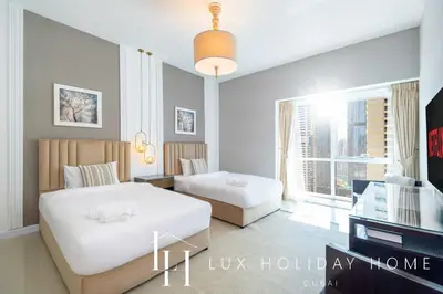 a bedroom with two beds and a living room with a tv at LUX The Al Seef Marina 4 bed Suite in Dubai