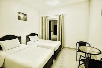 a hotel room with two beds and a table at Single Bed In Twin Room With Balcony For Female Guests Only in Dubai