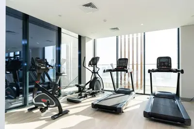 a gym with several tread machines in a room with windows at CitiHome - Studio Azizi Riviera in Dubai
