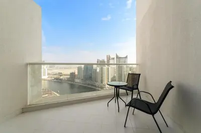 a balcony with two chairs and a table and a large window at ALiving Luxury Studio with Balcony Views Prive 2007B in Dubai
