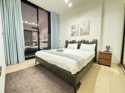 a bedroom with a large bed with blue curtains at DVR 1BR Apartment Available in Binghatti Corner in Dubai