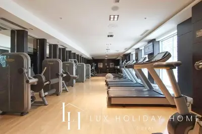 a gym with a row of treadmills and machines at LUX The Burj Khalifa Fountain View Suite 3 in Dubai
