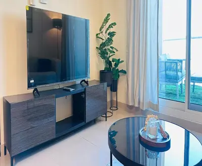 a living room with a large television and a table at Modern 1BR w Pool and Parking At Roxana Residence in Dubai