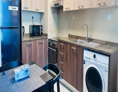 a kitchen with a washer and a sink and a table at Modern 1BR w Pool and Parking At Roxana Residence in Dubai