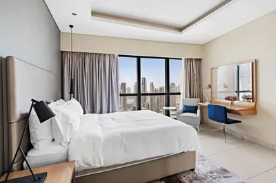 a bedroom with a white bed and a desk and chair at ALiving Luxury 3BR High-Rise I Burj Khalifa View I Paramount Towers, 6101 in Dubai