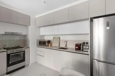 a kitchen with white cabinets and a stainless steel refrigerator at Luxury Stay at Marina Vista, Dubai Harbour in Dubai