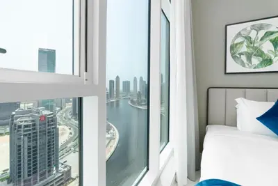 a bedroom with a window with a view of a city at BellaViu Holiday Homes-From City Rush to Calm -2BR Retreat in DAMAC Prive in Dubai