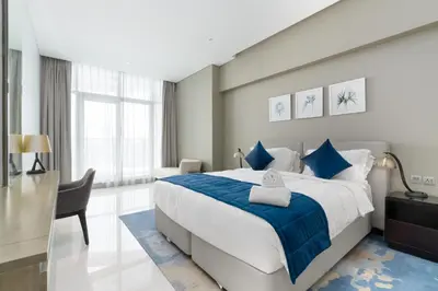 a bedroom with a large bed and a desk at BellaViu Holiday Homes-From City Rush to Calm -2BR Retreat in DAMAC Prive in Dubai
