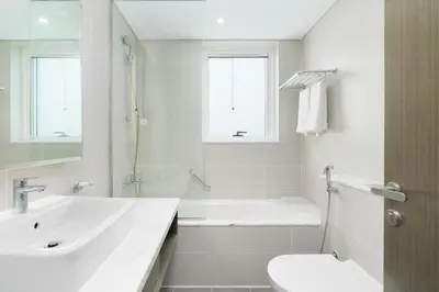 a white bathroom with a sink and a tub and a toilet at BellaViu Holiday Homes-From City Rush to Calm -2BR Retreat in DAMAC Prive in Dubai