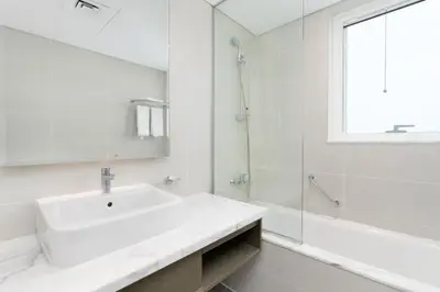 a white bathroom with a sink and a shower at BellaViu Holiday Homes-From City Rush to Calm -2BR Retreat in DAMAC Prive in Dubai