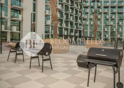 a group of barbecue chairs in front of a building at Bloomfields 1br Azizi Farhad Burj View Bliss in Dubai