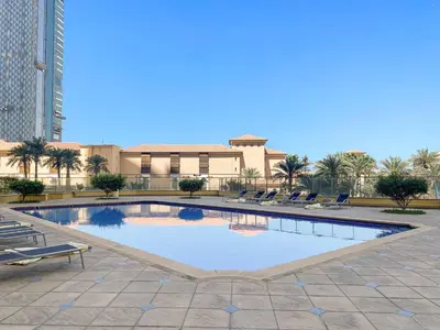 a large swimming pool with chairs and a building at 2-Bedroom Apartment Near To The Beach in Sadaf in Dubai