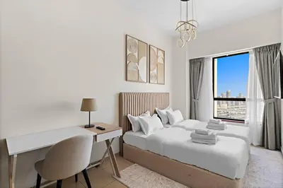 a white bedroom with a desk and a bed with a window at 2-Bedroom Apartment Near To The Beach in Sadaf in Dubai