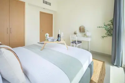 a white bedroom with a bed with a table at Frank Porter - Harbour Views T1 in Dubai