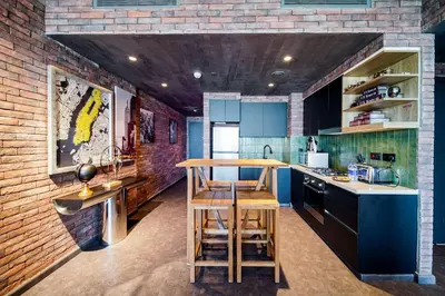 a kitchen with blue cabinets and a brick wall at PVH - Edgy and Modern Comfort 1BR Downtown Views 2 in Dubai