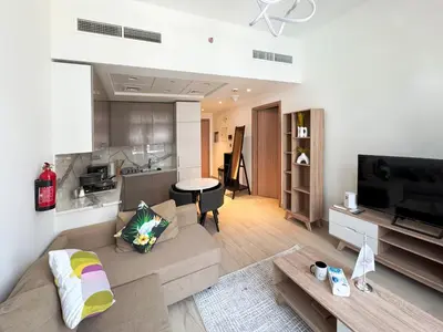 a living room with a couch and a tv and a kitchen at Azizi Riviera15 - Meydan by Golden Casa in Dubai