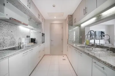 a kitchen with white cabinets and marble counter tops at EasyGo-Signature, City Center, City view in Dubai