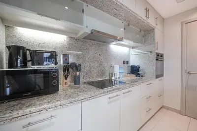 a kitchen with white cabinets and a black microwave at EasyGo-Signature, City Center, City view in Dubai