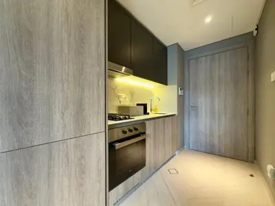 a kitchen with wooden cabinets and a stove top oven at Elegant and Cozy Studio Apartment - Amenities Access in Dubai