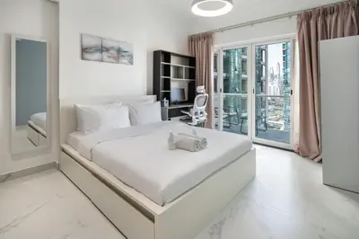 a white bedroom with a large bed and a desk at Luxury JLT 1BR Lakeview 5 min Metro & Marina in Dubai