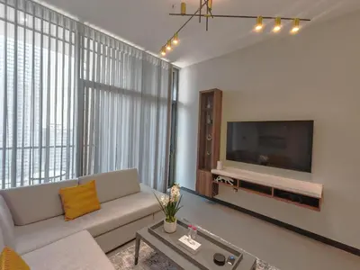 a living room with a couch and a flat screen tv at Brand New Luxury One Bedroom in Dubai