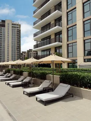 a row of lounge chairs with umbrellas in front of a building at Brand new and stylish 2BR with stunning views - Creek Palace in Dubai