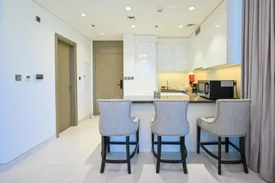 a kitchen with two bar stools and a counter at Crystal Escape 1BR Lagoon Access in Dubai