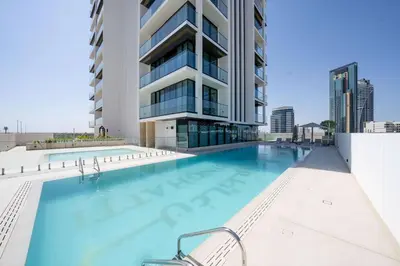a swimming pool in front of a building at Relax In Style 1br Haven In Binghatti Venus! in Dubai