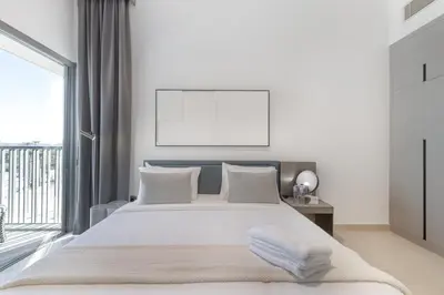 a white bedroom with a large bed and a window at ALiving Elegant 1BR Apartment with Balcony I MAG960 in Dubai