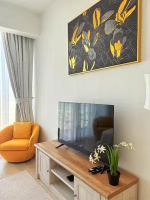 a living room with a television and a chair at Modern Fully Furnished Apartment in Bloom Tower B JVC - Easy Access to JBR, Circle Mall & Dubai Hills Mall in Dubai