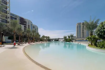a large swimming pool with palm trees and buildings at GuestReady - Modern design in Dubai Creek Harbour in Dubai