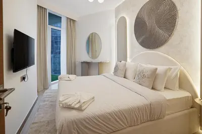 a bedroom with a white bed with a tv on a wall at 26- Apartment in Business Bay Dubai with Balcony & Pool in Dubai