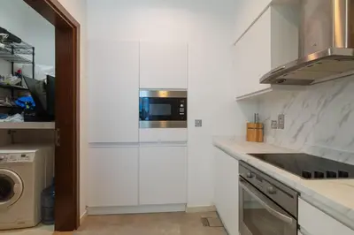 a kitchen with white cabinets and a washer and dryer at Modern 1BD, beautiful SeaView, Pool & Beach access in Dubai