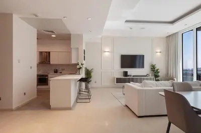 a living room with a white couch and a kitchen at Modern 1BD, beautiful SeaView, Pool & Beach access in Dubai
