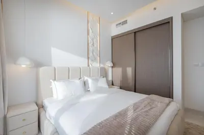 a white bedroom with a large white bed with white pillows at Grand Bleu I Private Beach I Palm Jumeirah, Sea & Sky Views I Infinity Pool I PS5 I by Skyline Serenity in Dubai