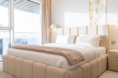 a large white bed in a room with a large window at Grand Bleu I Private Beach I Palm Jumeirah, Sea & Sky Views I Infinity Pool I PS5 I by Skyline Serenity in Dubai