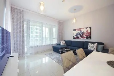 a living room with a blue couch and a table at Stylish 1BR plus study room with Queen bed in Dubai