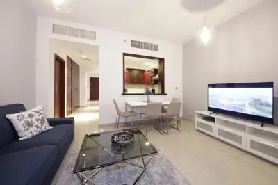 a living room with a blue couch and a tv at Stylish 1BR plus study room with Queen bed in Dubai