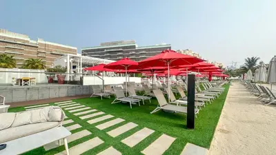 a row of chairs and red umbrellas on a patio at Best View Luxury 2BDR Palm Jumeirah, Beach & Pool in Dubai