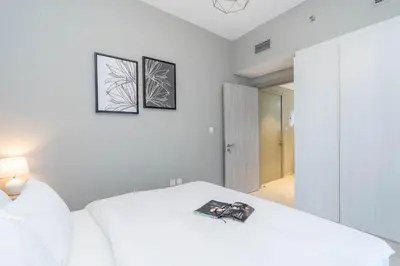 a bedroom with a white bed with two pictures on the wall at Perfect Location-For Work or Leisure in Dubai