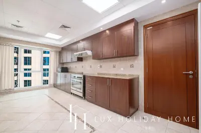 a kitchen with wooden cabinets and a large window at LUX The Al Seef Marina Suite 2 in Dubai