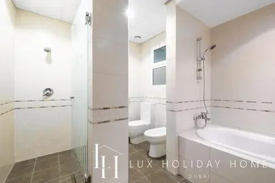 a bathroom with a toilet and a tub and a sink at LUX The Al Seef Marina Suite 2 in Dubai
