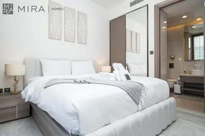 a white bedroom with a large bed and a bathroom at Stylish 1BR in Peninsula Five Views & Pool in Dubai
