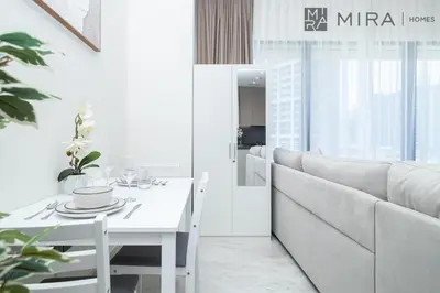 a white living room with a white table and a couch at Stylish 1BR in Peninsula Five Views & Pool in Dubai
