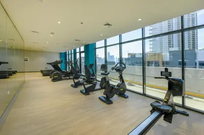 a gym with a row of treadmills and ellipticals at Studio with Pool and Community View, Near Soho Garden DXB and Meydan Golf Club, Azizi Riviera 43, Al Merkadh by Deluxe Holiday Homes in Dubai