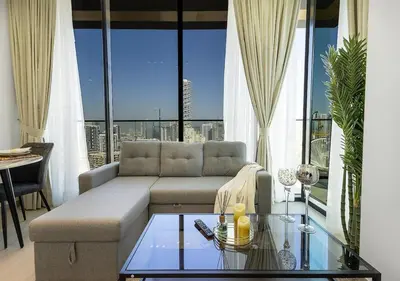 a living room with a couch and a glass table at Brand New Luxurious 1 BR with Garden, Gym, Pool and Open View in Dubai