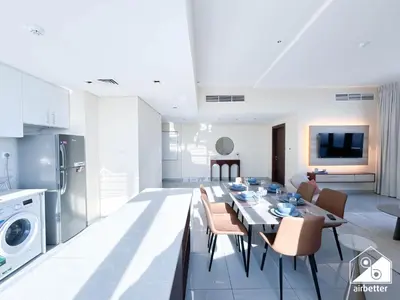 a kitchen and living room with a table and chairs at Cozy One-Bedroom in O2 Tower, JVC in Dubai