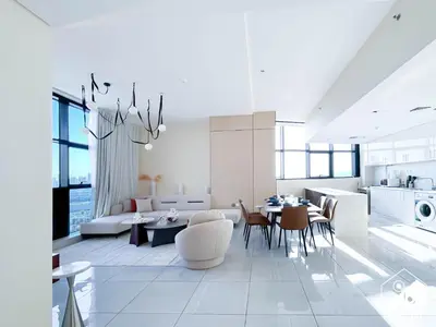 a white living room with a table and a kitchen at Cozy One-Bedroom in O2 Tower, JVC in Dubai