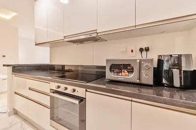 a kitchen with white cabinets and a microwave at DreamShoma-1BR Stunning Canal View in Dubai